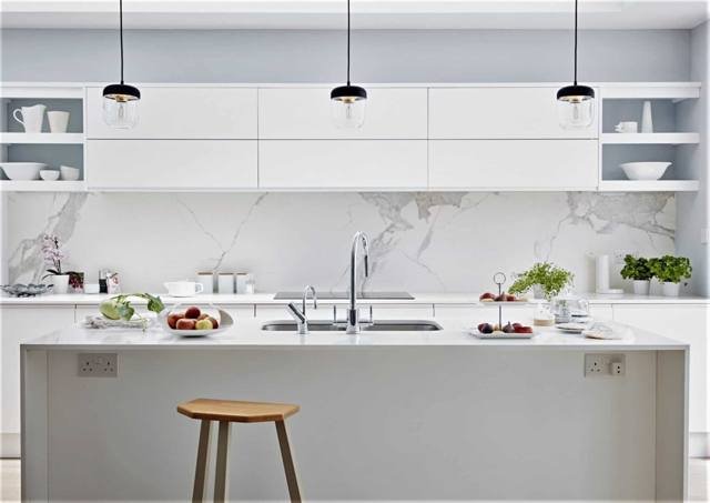A white kitchen with a stone splashback and island