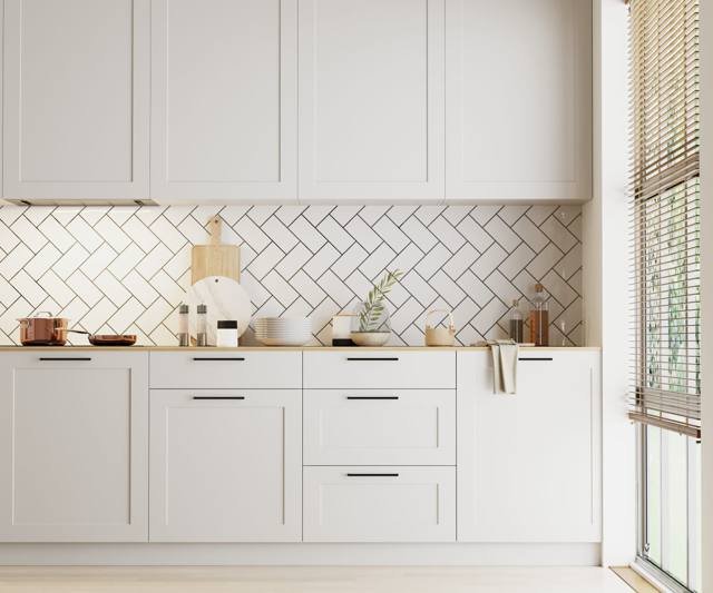 A light grey kitchen with a herringbone tile splashback